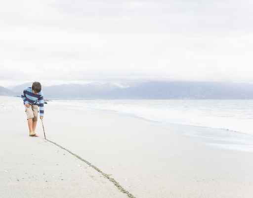 Boy Drawing line in the sand